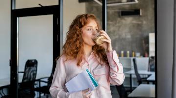 Vrouw met kop koffie en schrijfblok